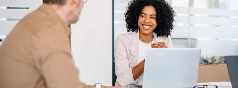 A joyful female professional with curly hair shares a warm smile while engaging in a productive conversation, Training